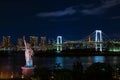 Odaiba`s Rainbow Bridge and Tokyo Tower seen in the distant against night sky and Statue of Liberty in foreground Royalty Free Stock Photo