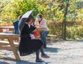 ODAWARA, JAPAN - NOVEMBER, 11, 2017: Woman in the park on a bench under an umbrella. Copy space for text.