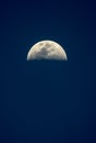 Odd vertical view of a clear bright half moon in a blue night sky Royalty Free Stock Photo