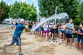 The guy pours water from a bucket on the crowd of teenagers before the water sports competition in the summer camp