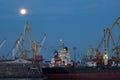 ODESSA, UKRAINE - August 2016: ship unloading at port terminal under full moon in evening with cranes containers and Royalty Free Stock Photo