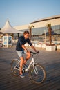 ODESSA, UKRAINE - AUGUST 06, 2015: Young man cycling at the beach at sunrise sky at wooden deck summer time Royalty Free Stock Photo