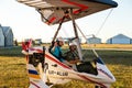 Odessa, Ukraine - July 14, 2016: Young smiling girl with pilot preparing to start the flight at motor hang glider.