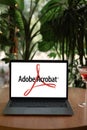 Odessa, Ukraine - June 14, 2023: Laptop computer in summer cafe displaying logo of Adobe Acrobat, application software