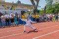 Odessa, Ukraine - June 9, 2020: Young female athlete wearing a mask and white fencing costume on the track of stadium during a