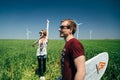 ODESSA, UKRAINE - MAY, 20 2015: Cute young hipster couple is kidding in the middle of green field with a surfboard, happy smiling Royalty Free Stock Photo