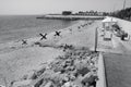 Odessa, Ukraine -2022: Metal military barriers, anti-tank hedgehogs on sea city beach. Vacationers sunbathe next to iron anti-tank