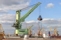 Green floating crane of Liebherr company with a raised bucket in the seaport of Odessa