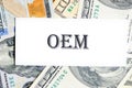 OEM original equipment manufacturer concept. Text on a white business card against the background of money, a business concept