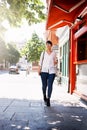 Off on a mission again. a beautiful young woman walking on a sidewalk past shops outside in a town during the day. Royalty Free Stock Photo
