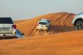 Off-road adventure with SUVs driving in Arabian Desert at sunset. Traditional entertainment for tourists with vehicle bashing thro