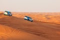 Off-road adventure with SUVs driving in Arabian Desert at sunset. Traditional entertainment for tourists with vehicle bashing thro Royalty Free Stock Photo