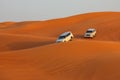 Off-road adventure with SUVs driving in Arabian Desert at sunset. Traditional entertainment for tourists with vehicle bashing thro