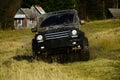 Off road car in black color takes part in racing. Cross country rallying or rally raid near countryside hut aside forest Royalty Free Stock Photo