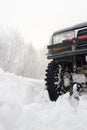 Off-road car wheel on snow in snowdrift against background of winter nature. Extreme winter weather, sports, driving