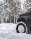 Off-road car wheel on the snow in snowdrift, winter forest. Snow car for extreme winter weather, sports, travel, driving Royalty Free Stock Photo