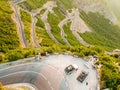 Off road cars on cliff above serpentine road in Albanian mountains near Rrapsh