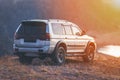 Off road crossover car standing on mountain terrain at sunset near wild lake. Travel and journey 4wd suv