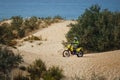 off-road motorcycle enduro motocross rider on sand dune, blue sea background