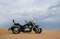 Off-road motorcycle standing still in the open desert beneath heavy clouds Royalty Free Stock Photo
