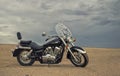 Off-road motorcycle standing still in the open desert beneath heavy clouds Royalty Free Stock Photo