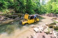 Off-road Russain car stuck in mountain river at breakdown while jeeping. Driver repairs auto with lifted hood