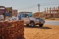 Off-road vehicle in engine failure at the roadside in front of a pile of fresh clay bricks in a suburb of Khartoum Royalty Free Stock Photo