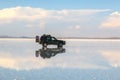 off road vehicle over a reflective salt flat ground. Clouds and sky, Uyuni, Bolivia