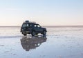 off road vehicle over a reflective salt flat ground. Clouds and sky, Uyuni, Bolivia