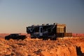 Off-road vehicle with a recreational vehicle (RV) parked at the end of a dirt road, next to a SUV.