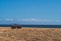 Off road vehicle on sandy beach against blue sky and ocean