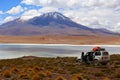 An off road vehicle stopped in front of a lake and in the background mountains. Adventure in Bolivia highlands in the Andes. Royalty Free Stock Photo