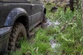 Off-road vehicle stuck in the mud. Dirty offroad car in swamp. Adventure travel concept. 4x4 SUV got bogged. Journey, tourism