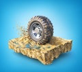 Off road wheel on the piece of ground on a blue background.