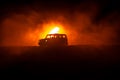 Off roader jeep silhouette on dark toned foggy sky background. Car with light at night.