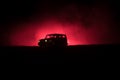 Off roader jeep silhouette on dark toned foggy sky background. Car with light at night.