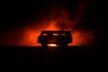 Off roader jeep silhouette on dark toned foggy sky background. Car with light at night.