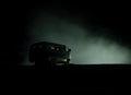 Off roader jeep silhouette on dark toned foggy sky background. Car with light at night