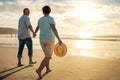 Off into the sunset they go. a mature couple holding hands while walking on the beach. Royalty Free Stock Photo