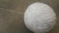 Off white ball of threads wool yarn for knitting on grey floor background Royalty Free Stock Photo