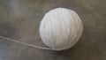 Off white ball of threads wool yarn for knitting on grey floor background Royalty Free Stock Photo