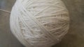 Off white ball of threads wool yarn for knitting on grey floor background Royalty Free Stock Photo