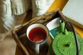 Off-white knitted sweater hanging over wooden chair, mug with red fruit tea, pot in tray by window, old book autumn, fall Royalty Free Stock Photo