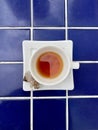 An off white porcelain cup and saucer with delicious herbal tea on a blue tile Royalty Free Stock Photo