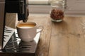 ÃÂ¡offee machine and white cup near window at daytime in coffee shop, cafe or restaurant. Jar of hazelnuts on background Royalty Free Stock Photo