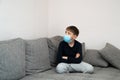 Offended angry boy sits in mask at home in quarantine. Looks at place for text. Epidemic coronavirus COVID19. Place for your text