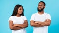 Offended black couple standing with crossed arms, blue studio wall Royalty Free Stock Photo