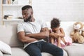 Offended black girl crying, sitting on sofa next to dad Royalty Free Stock Photo