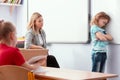 Offended child stands with his arms folded in the classroom