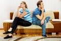 Offended couple sitting back to back on sofa